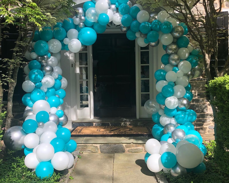 Arch of blue and white balloons over door to house