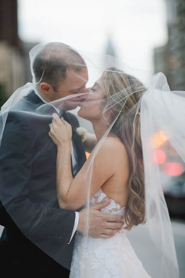 Bride and groom kiss under flowing veil
