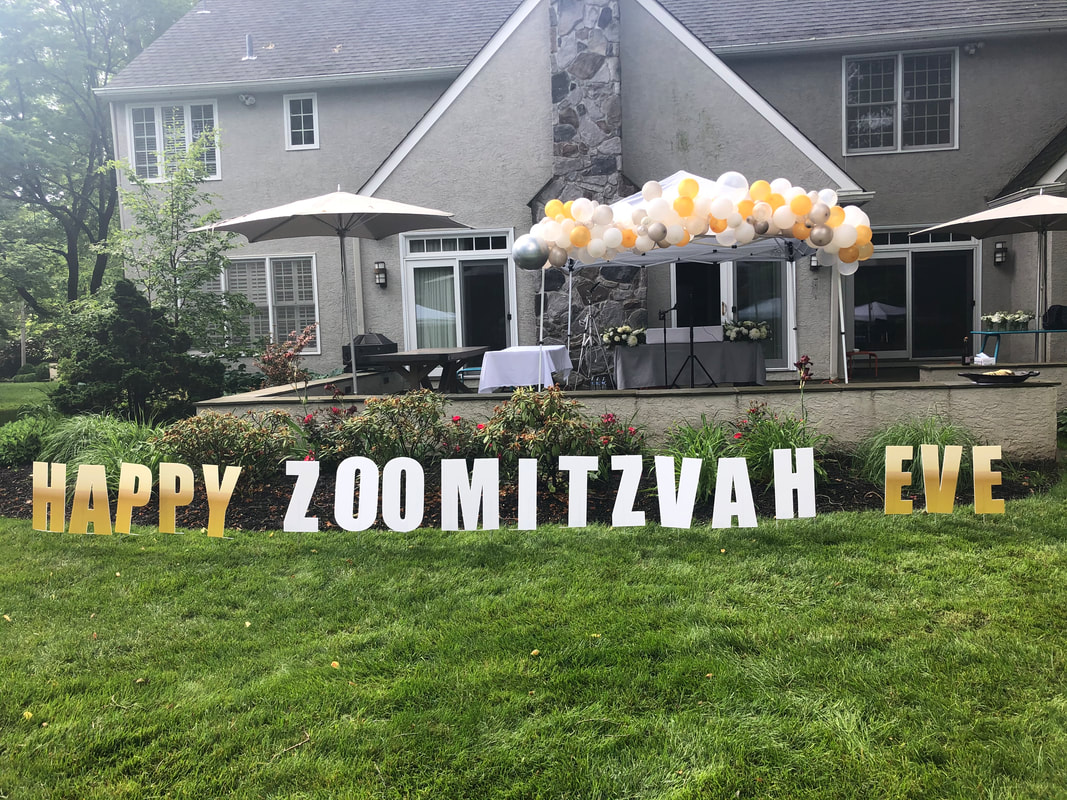 Picture of house and lawn with balloon canopy and signs reading 